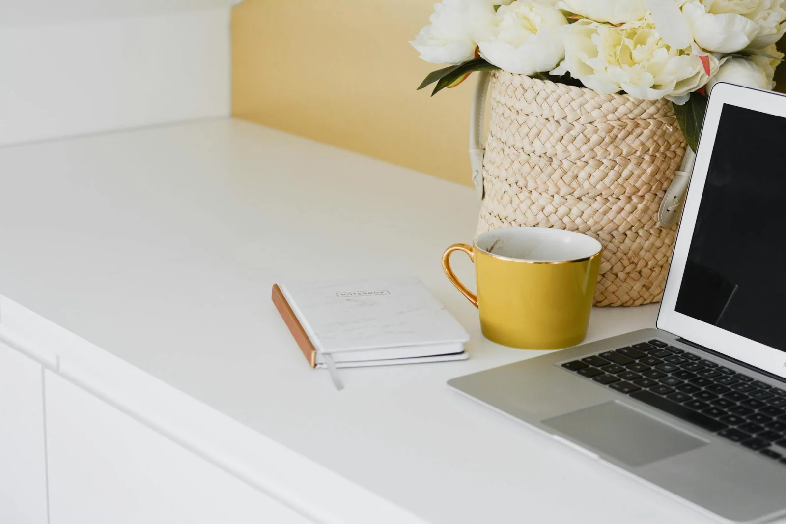 Overhead view of closed notebook, pen, and smartphone on white desk